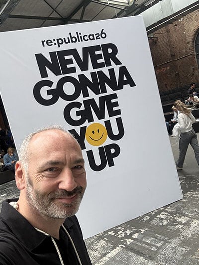 Prof. Michael Schwertel vor dem Never Gonna Give You Up Logo der re:publica 2026 Berlin